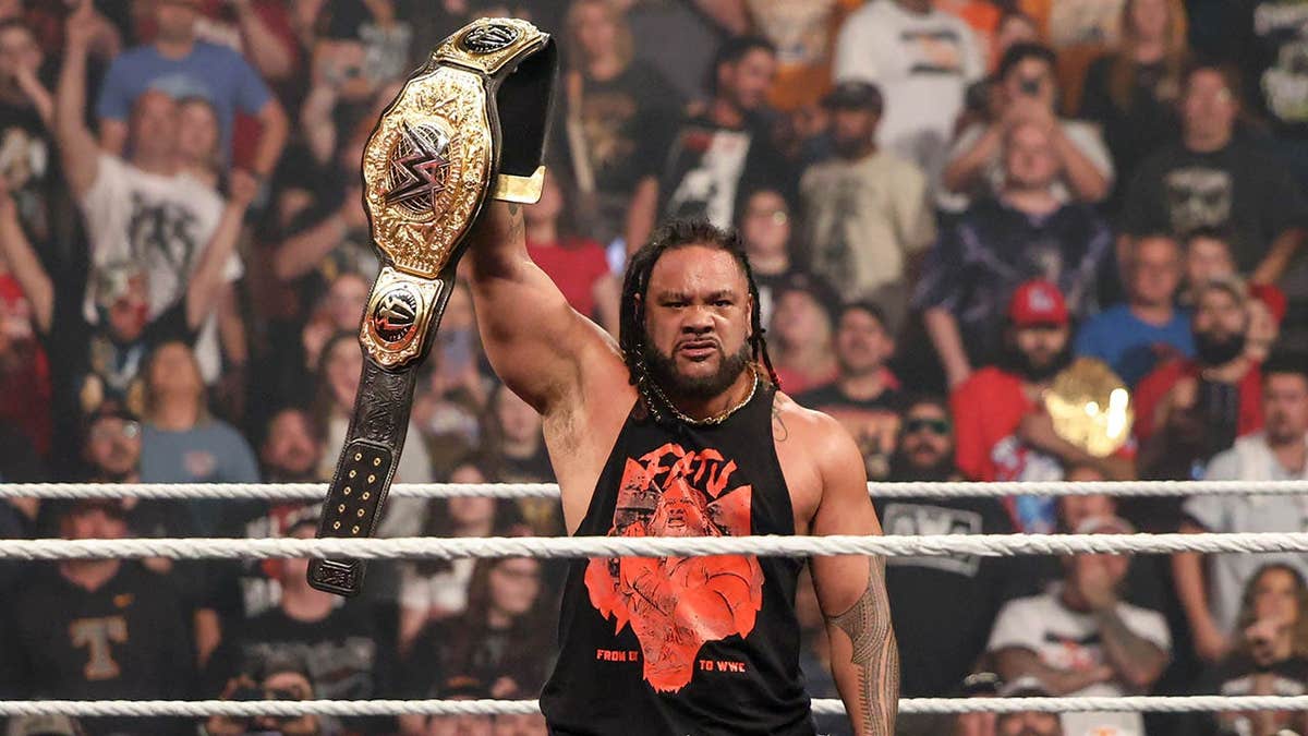Jacob Fatu holding up the World Heavyweight Champion belt in an arena.