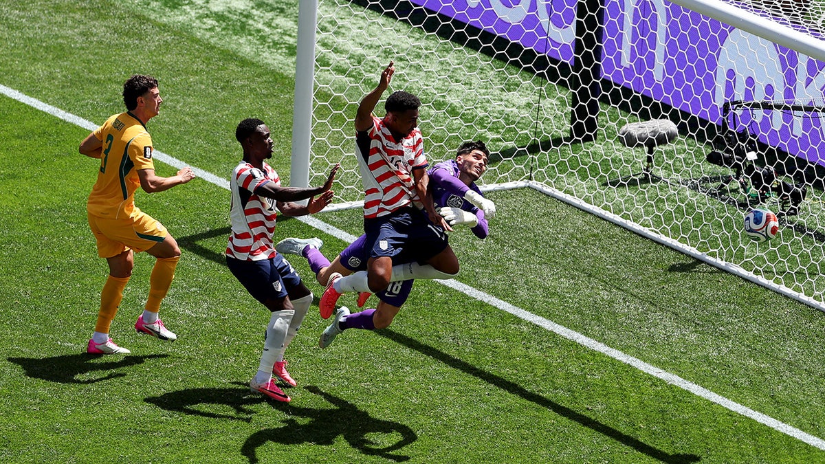 United States' Alex Freeman heads the ball past Australia goalkeeper Patrick Beach in a soccer match.