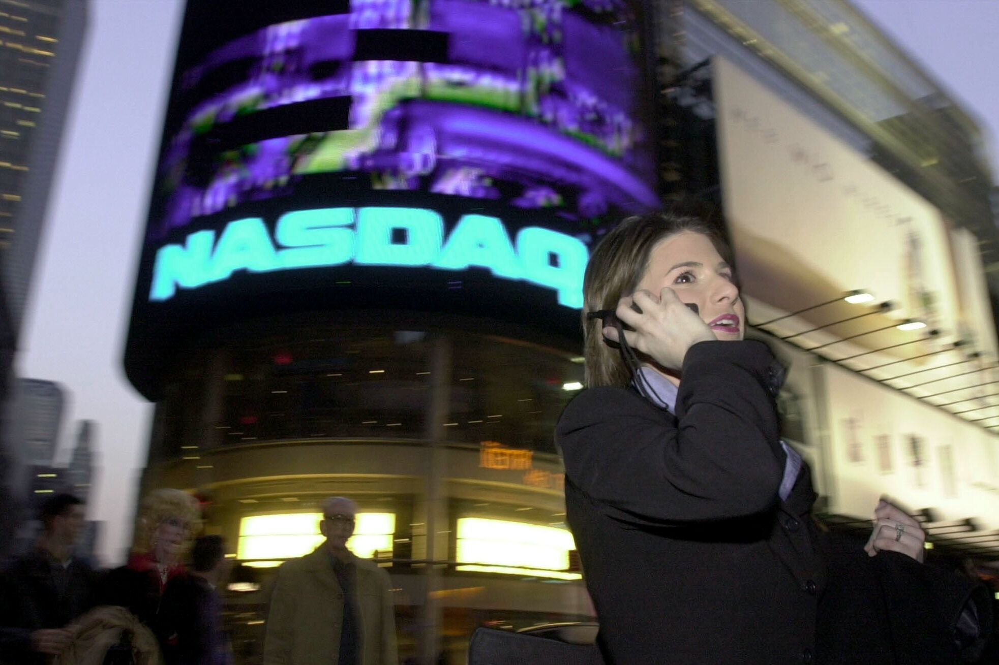 The tech-heavy Nasdaq stock index has lately been on a roller coaster. In this photo taken in 2000, a woman walks past the Nasdaq sign in New York City