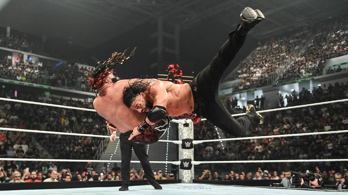 Roman Reigns performing a spear on Jacob Fatu in a wrestling ring.