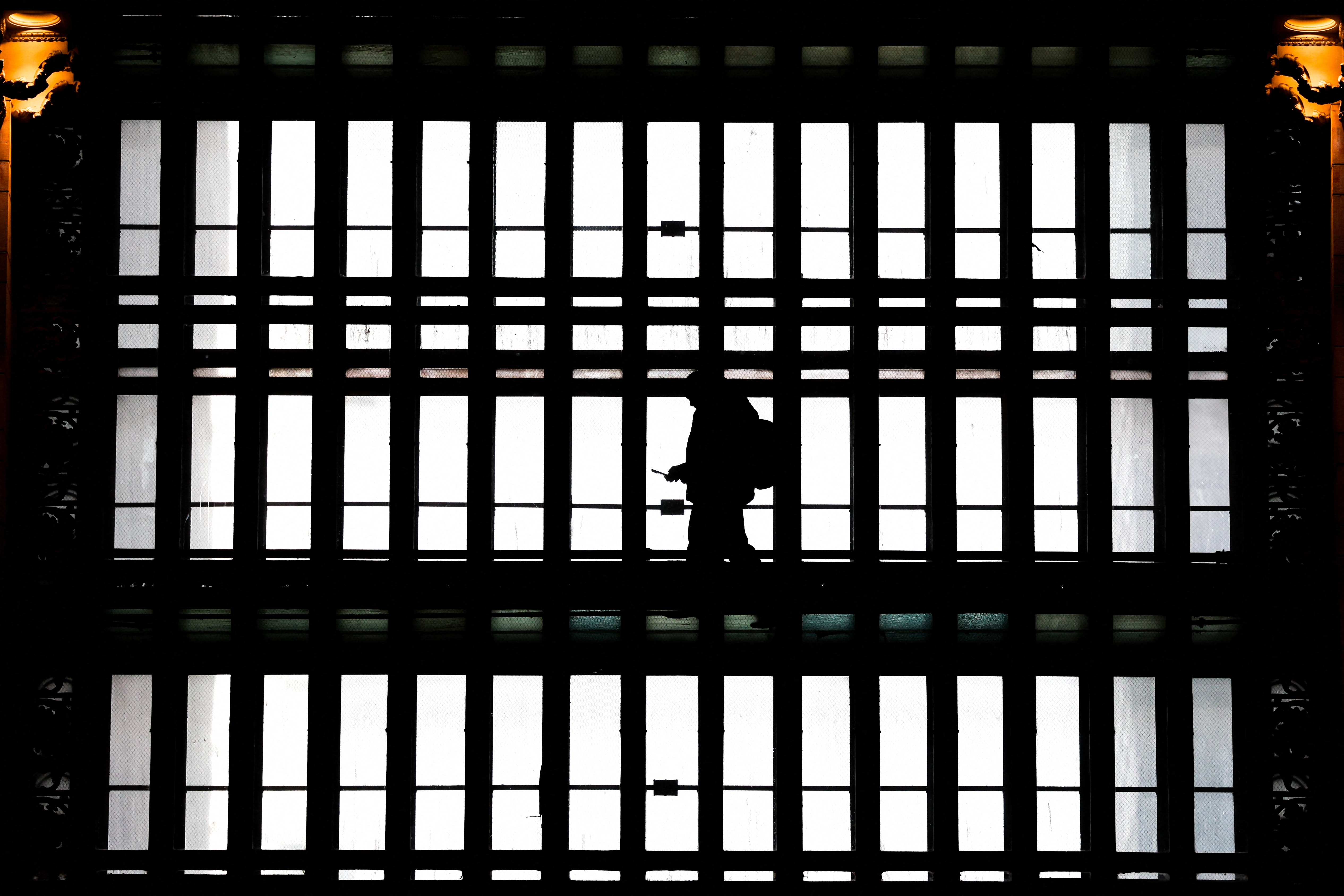In this file photo, a man using a smartphone passes through the arched windows at Grand Central Terminal in New York City on March 24, 2025.
