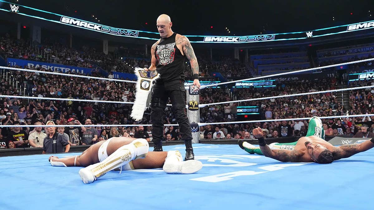 Baron Corbin looks down at Trick Williams in the ring.