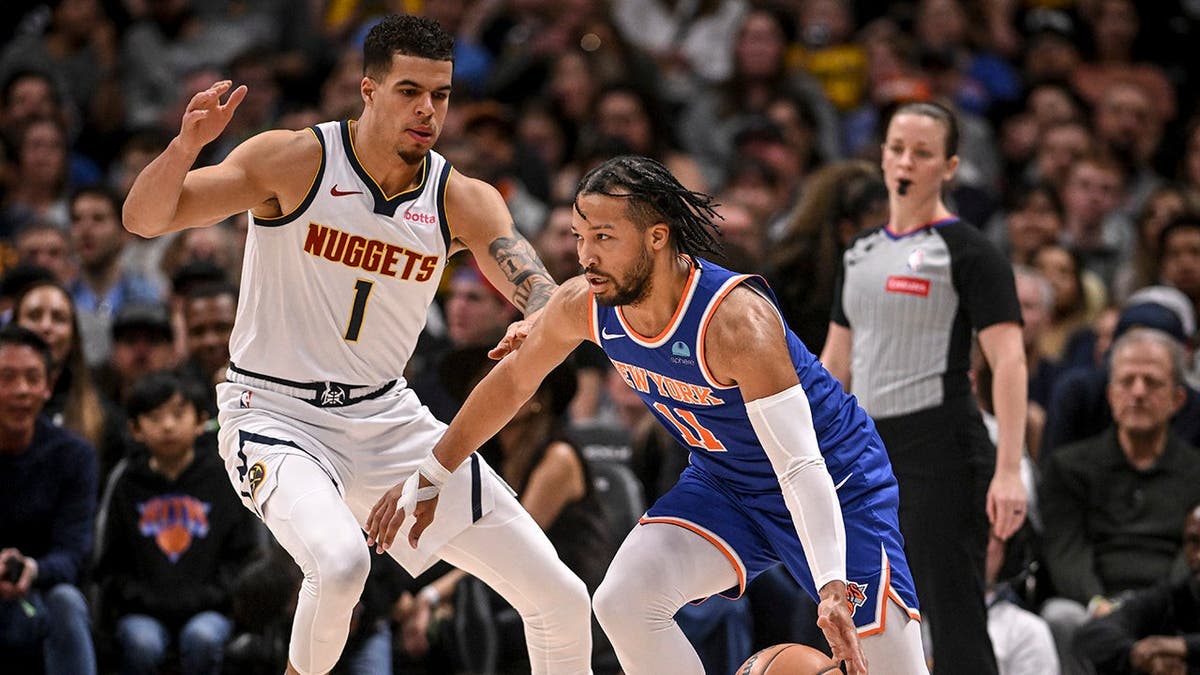Jalen Brunson drives on Michael Porter Jr. during a basketball game at Ball Arena.