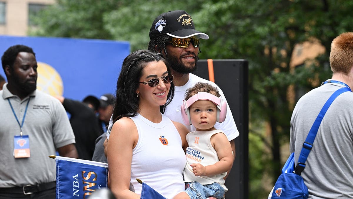 Jalen Brunson stands with his wife Ali Marks and daughter Jordyn James Brunson at a New York Knicks parade.