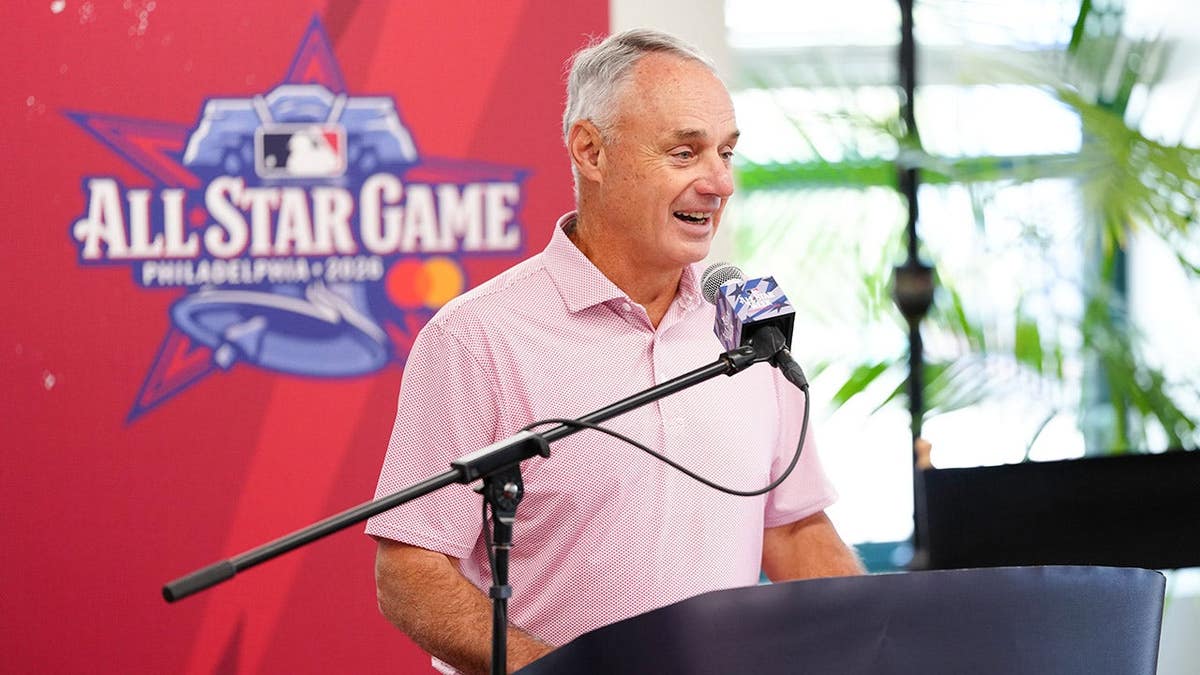 Robert D. Manfred speaks indoors at a podium.