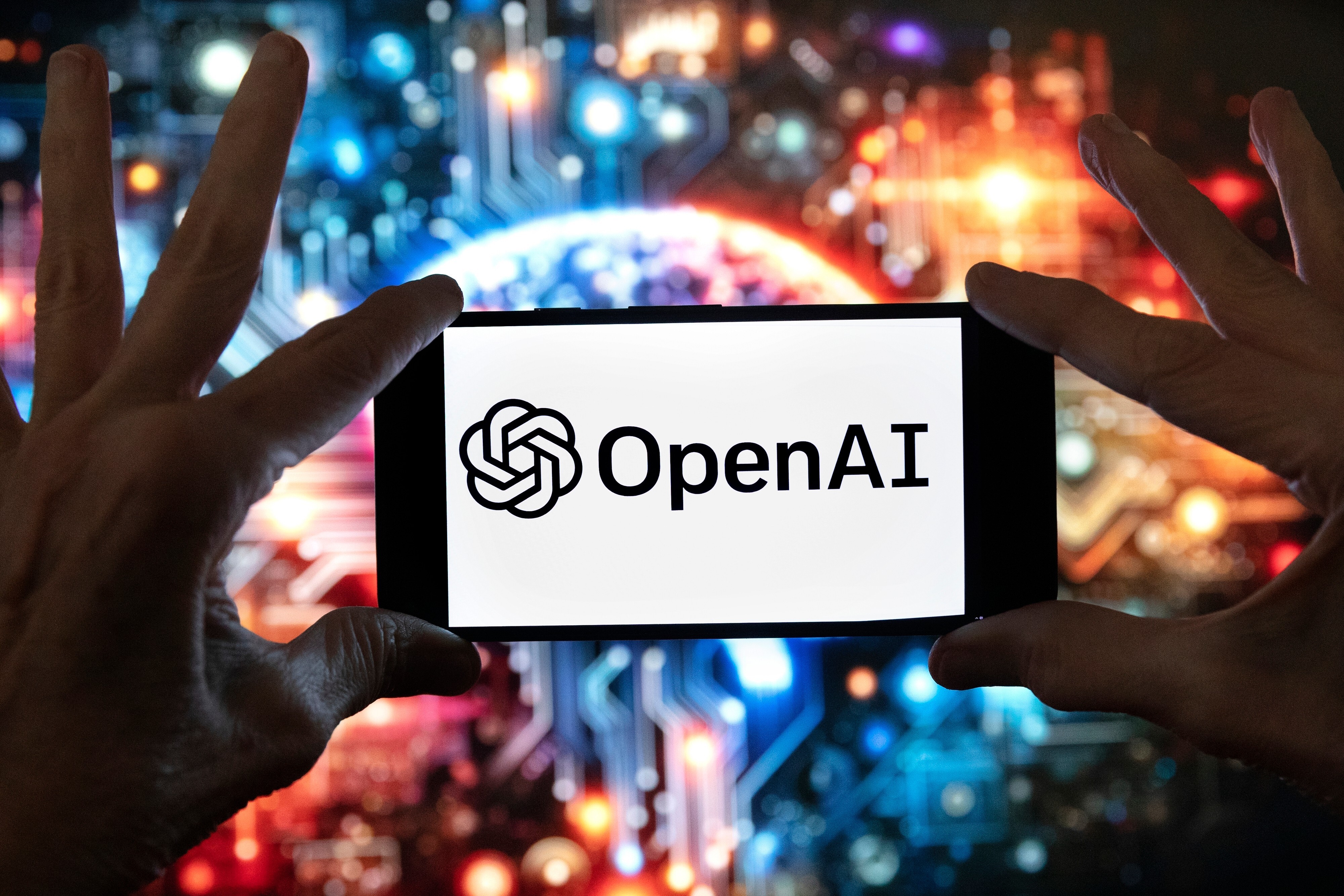 FILE - The OpenAI logo is displayed on a cell phone in front of an image generated by ChatGPT