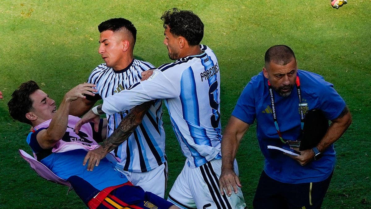 Gavi falls as he scuffles with Leandro Paredes and Thiago Almada on the field.
