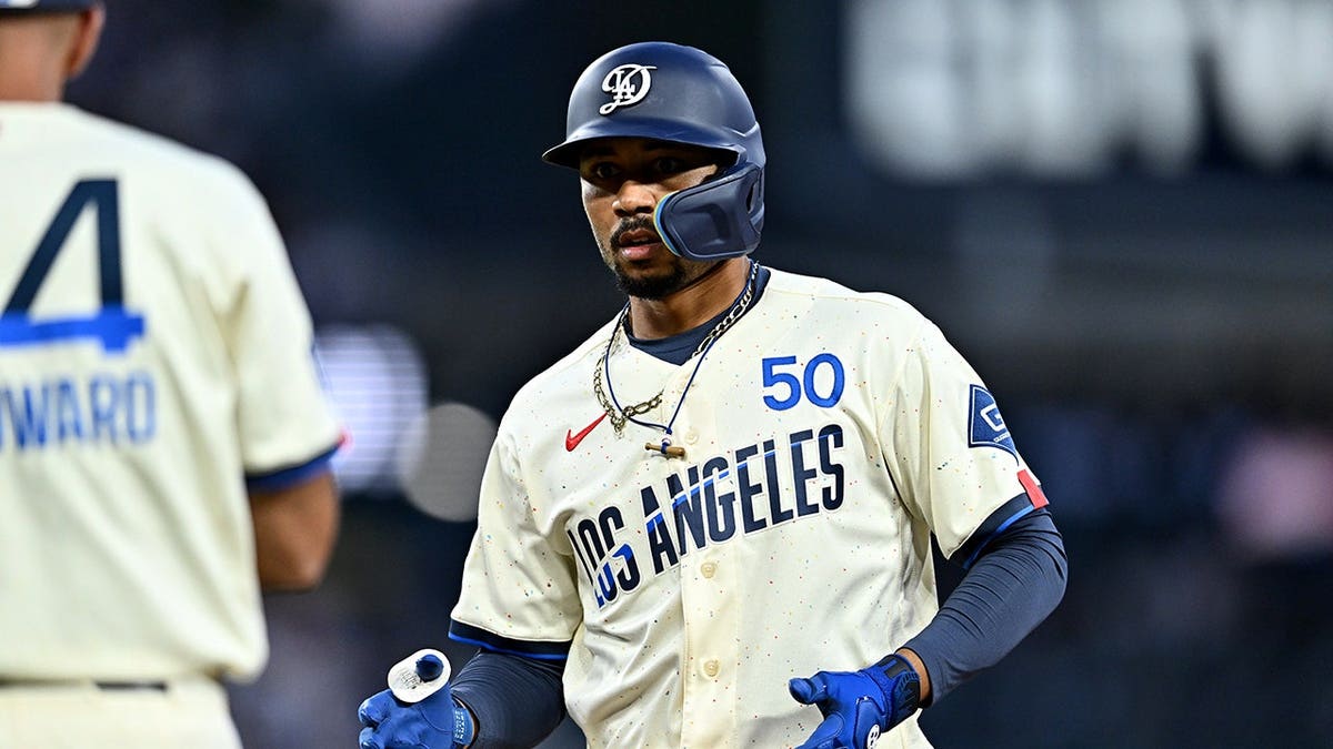 Mookie Betts is greeted by Chris Woodward at first base after a hit at Dodger Stadium.