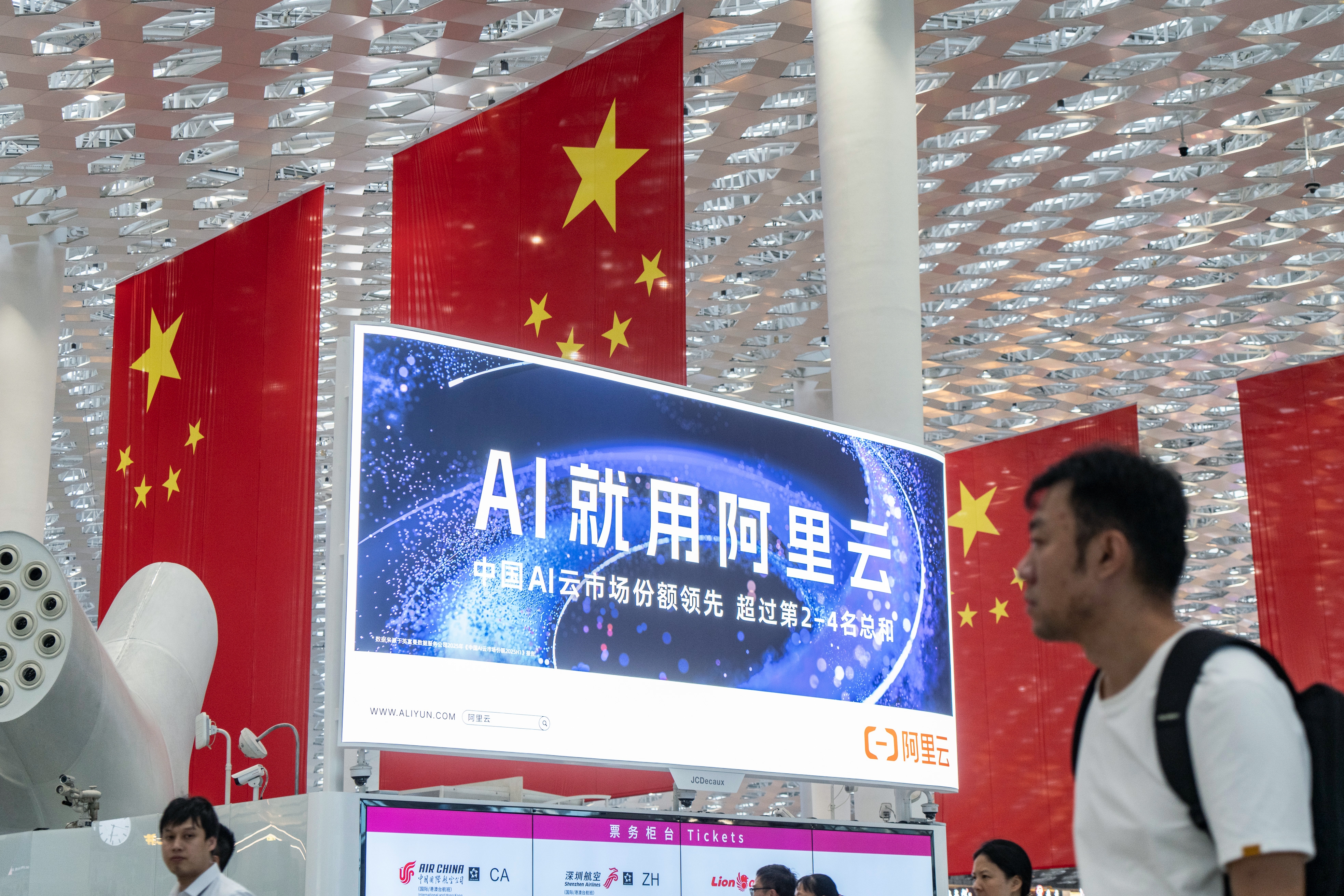 Travelers walk past an Alibaba Cloud advertisement at Shenzhen Bao