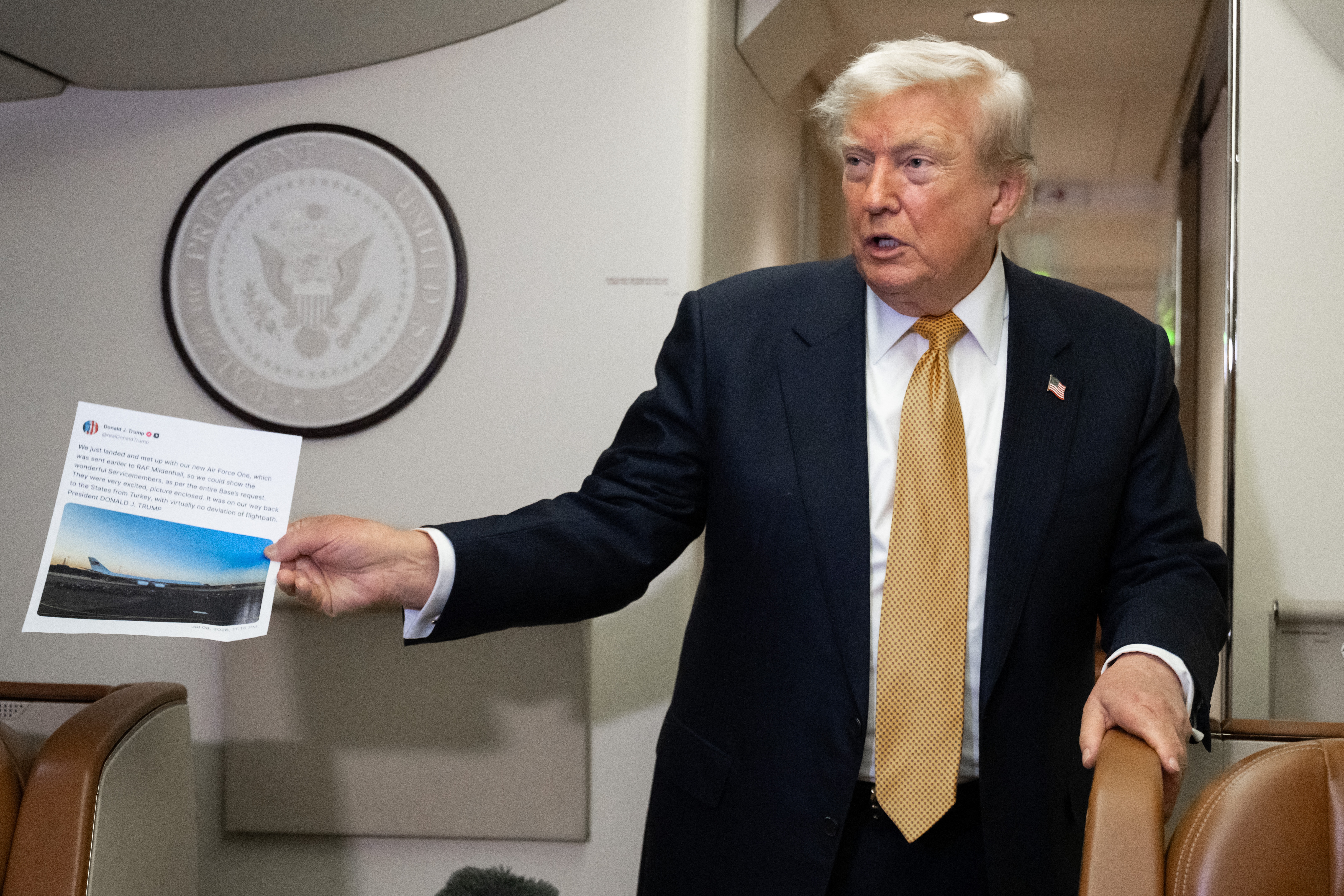President Donald Trump holds up a copy of his Truth Social post about Air Force One as he speaks with the media aboard Air Force One on July 8, 2026. The president