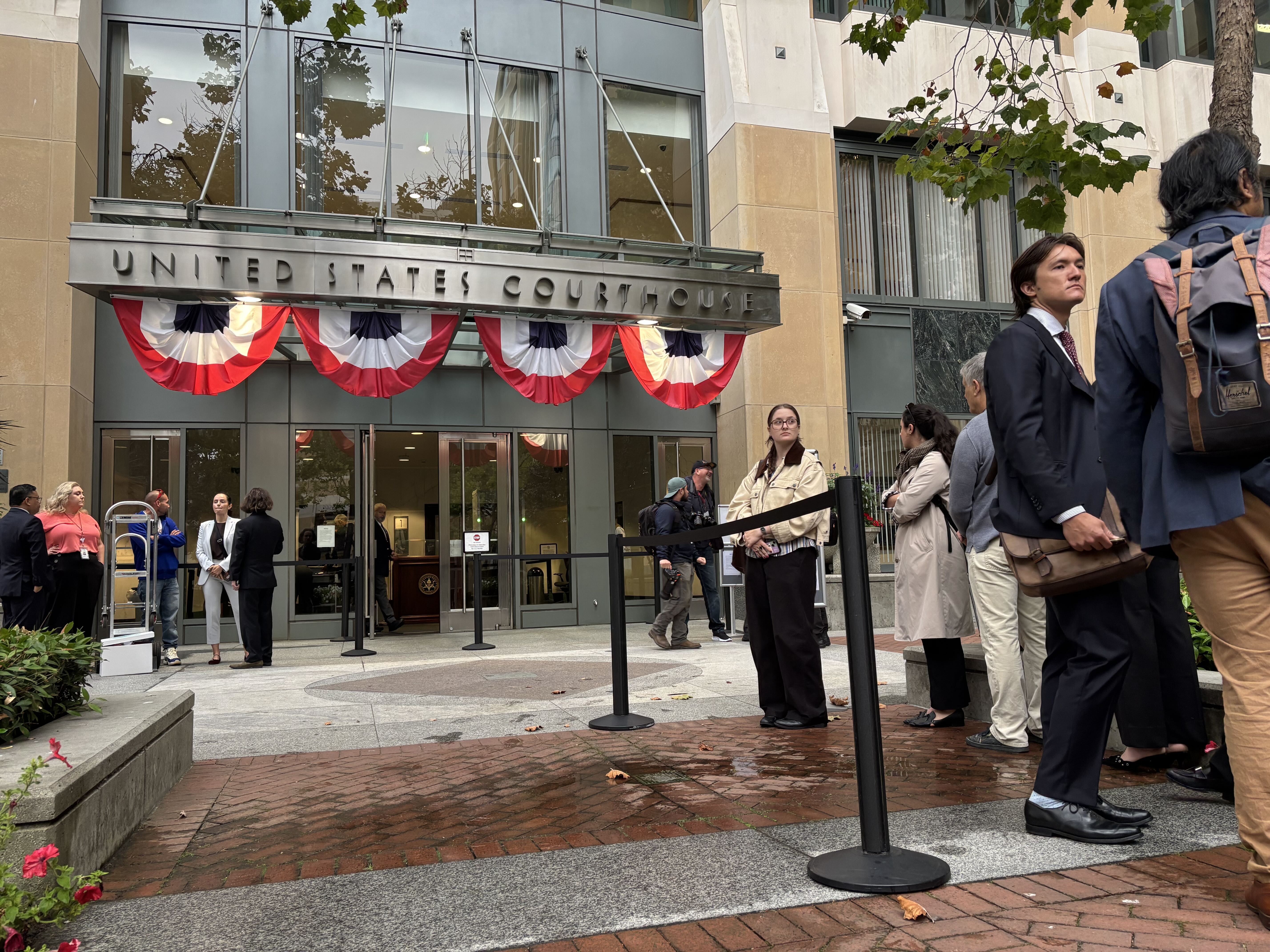 People line up outside the Oakland, California federal courthouse ahead of opening arguments in the trial that four state attorneys general are bringing against Meta Platforms, Inc.