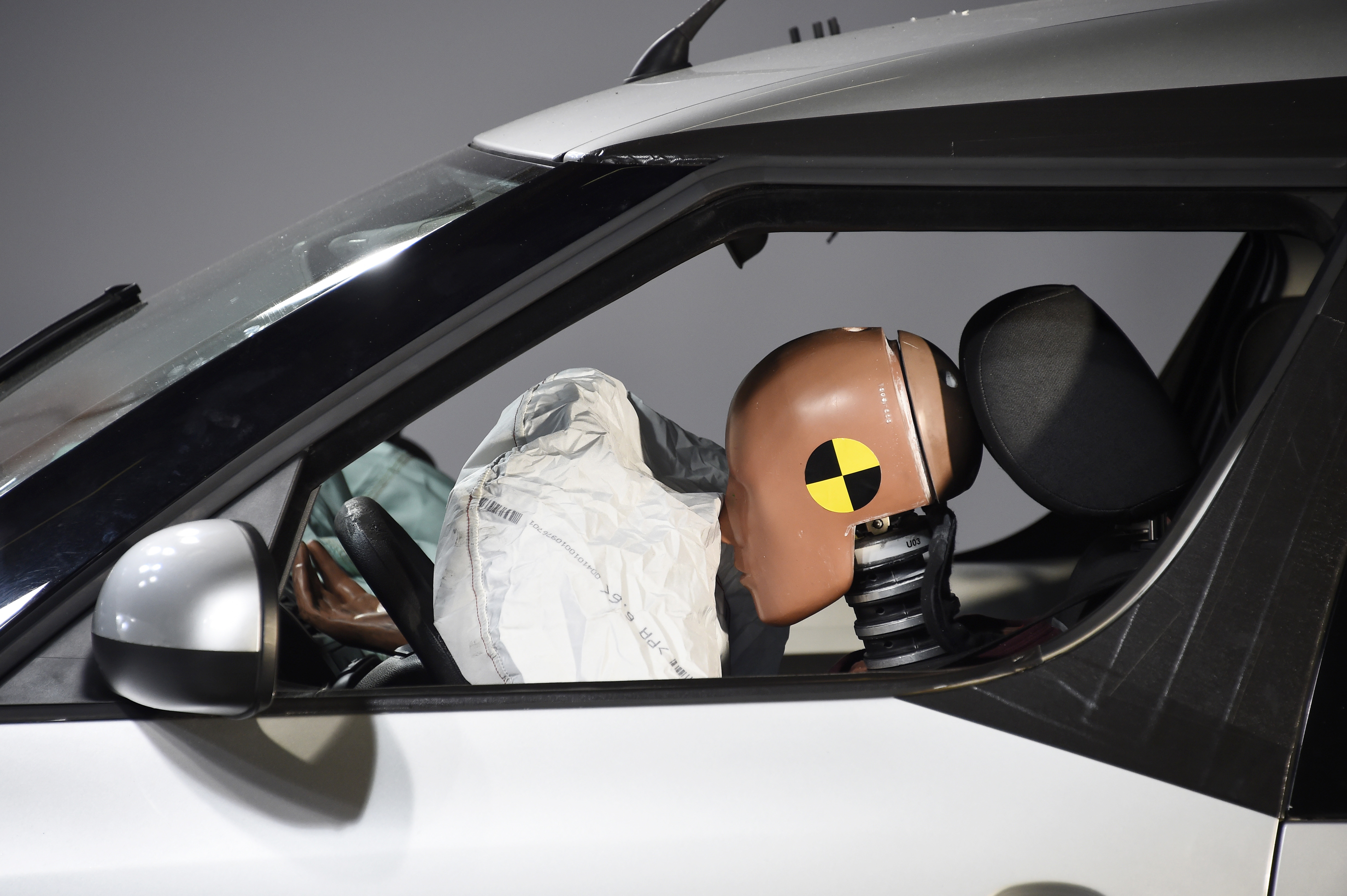 A car and its airbag are pictured after a frontal crash test with another car, without a safety belt buckled in the back seat, as part of France